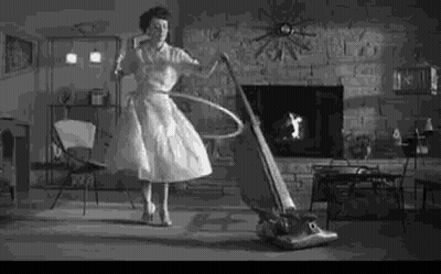 Woman Hula Hooping While Vacuum Cleaner Cleans Floor GIF