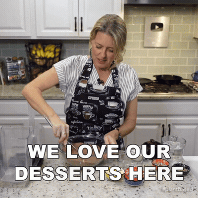 Woman In Apron Preparing Dessert Saying We Love Our Desserts GIF