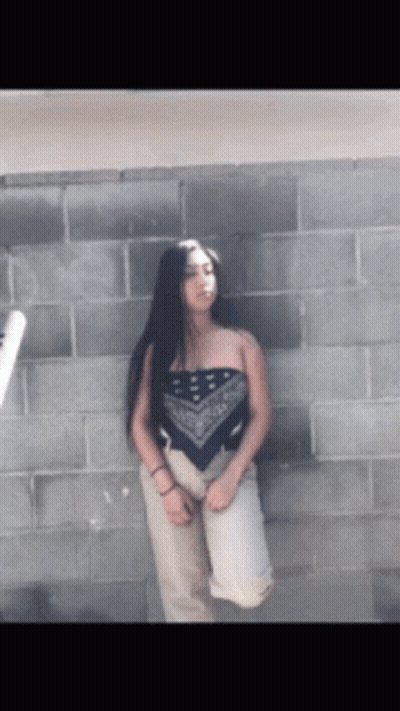 Woman In Bandana Top In Front Of Brick Wall GIF