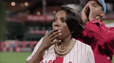 Woman In Baseball Uniform Covering Mouth While Man Shouts GIF