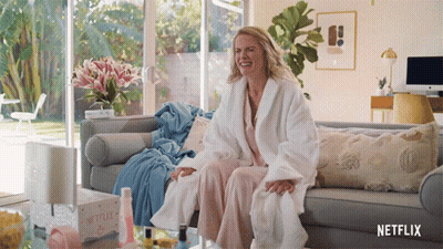 Woman In Bathrobe Sitting On Couch With Netflix Box GIF