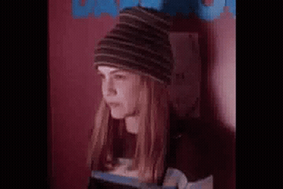 Woman In Beanie And Striped Shirt Standing By Wall GIF