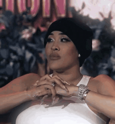 Woman In Beanie And White Tank Top Sitting With Hands Folded GIF