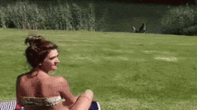 Woman In Bikini Sitting In Grass GIF