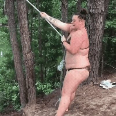 Woman In Bikini Swinging On Rope In Woods GIF
