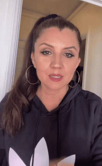 Woman In Black Adidas Hoodie And Earrings Looking At Camera GIF