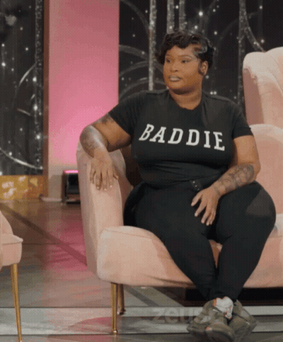 Woman In Black Baddie Shirt Sitting In Chair GIF