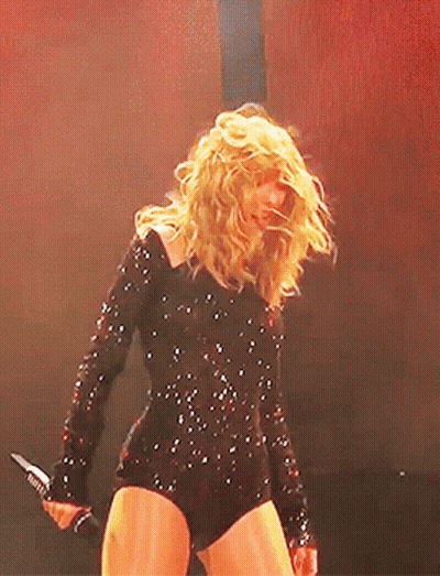Woman In Black Bodysuit Holding Microphone On Stage GIF