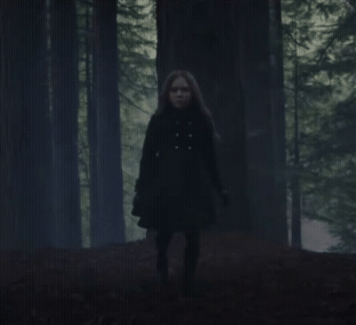 Woman In Black Coat Running Through Forest GIF
