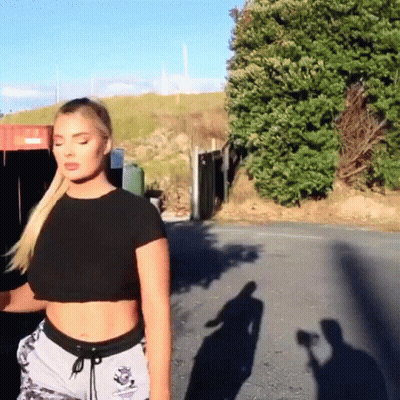 Woman In Black Crop Top And Gray Shorts Walking Down Street GIF