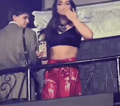 Woman In Black Crop Top And Red Leather Pants Holding Cell Phone On Balcony GIF