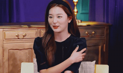Woman In Black Dress And Headband Sitting At Table GIF