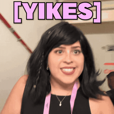 Woman In Black Dress And Pink Lanyard Smiling Beside Yikes Sign GIF