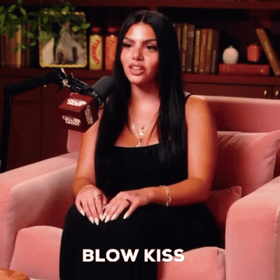 Woman In Black Dress Blowing Kiss In Pink Chair GIF