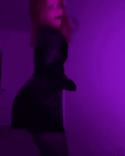 Woman In Black Dress Dancing Under Purple Lights GIF