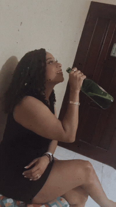 Woman In Black Dress Drinking From Green Bottle GIF