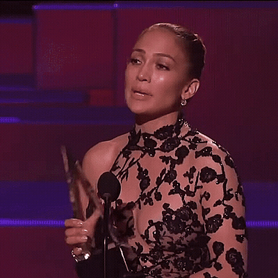 Woman In Black Dress Flexing At Microphone GIF
