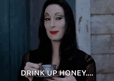Woman In Black Dress Holding Coffee Saying Drink Up Honey GIF