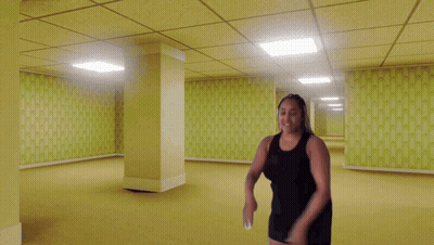 Woman In Black Dress In Empty Yellow Hallway GIF
