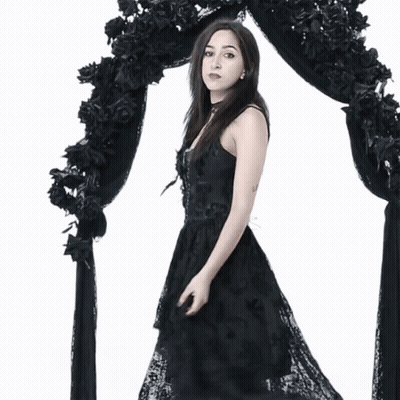 Woman In Black Dress In Front Of Black Arch GIF