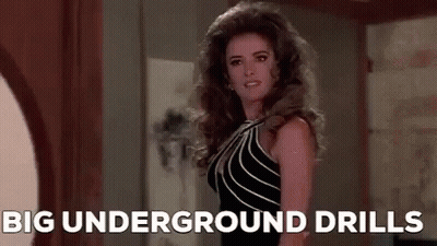 Woman In Black Dress In Hallway With Big Underground Drills GIF