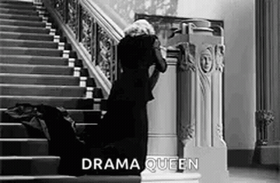 Woman In Black Dress Kneeling On Stairs Black And White GIF