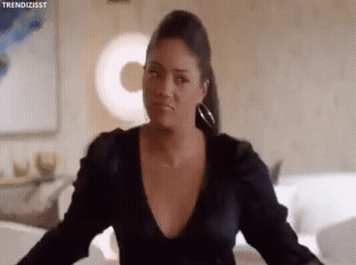 Woman In Black Dress Looking At Camera In Living Room GIF