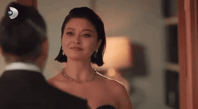 Woman In Black Dress Looking At Man In Tuxedo In Mirror GIF