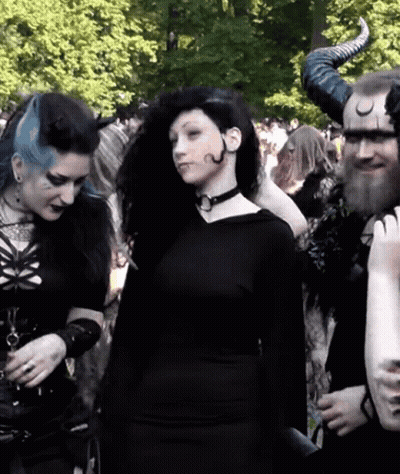 Woman In Black Dress Next To Man With Horns GIF