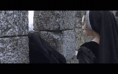 Woman In Black Dress Next To Stone Wall GIF