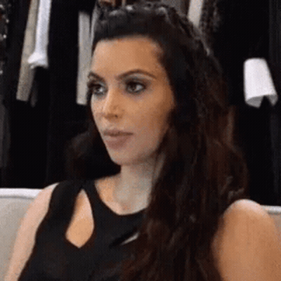 Woman In Black Dress On Couch Looking At Camera GIF