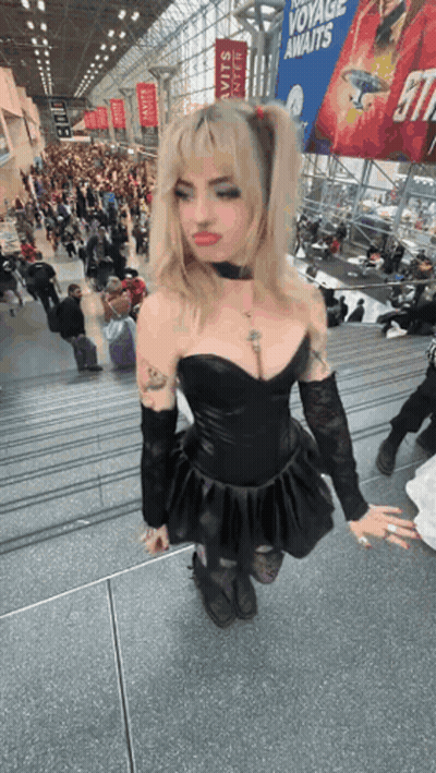 Woman In Black Dress On Stairs In Front Of Crowd GIF