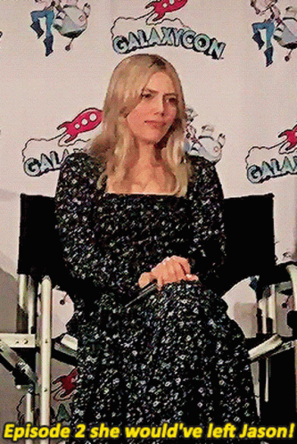 Woman In Black Dress Sitting In Front Of Galaxycon Sign GIF
