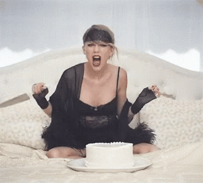 Woman In Black Dress Sitting On Bed With Cake GIF