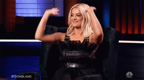 Woman In Black Dress Sitting With Arms Up GIF