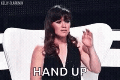 Woman In Black Dress Sitting With Hands Up Saying Hand Up GIF
