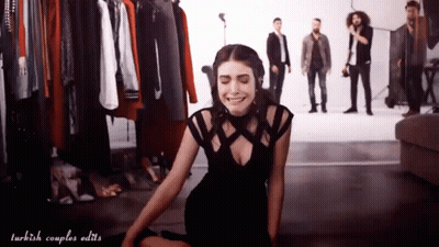 Woman In Black Dress Sitting With Men Standing GIF