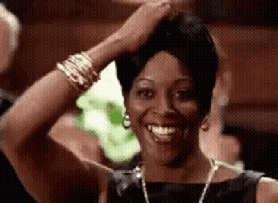 Woman In Black Dress Smiling And Holding Hair GIF