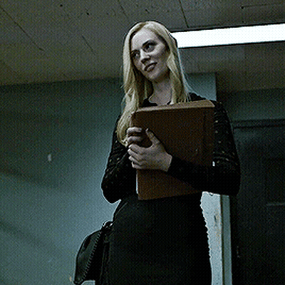 Woman In Black Dress Smiling Holding Folder GIF