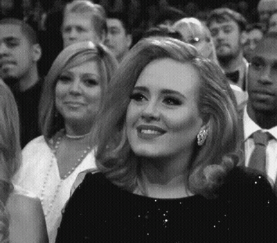 Woman In Black Dress Smiling In Crowd GIF