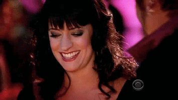 Woman In Black Dress Smiling In Front Of Man In Pink Shirt GIF