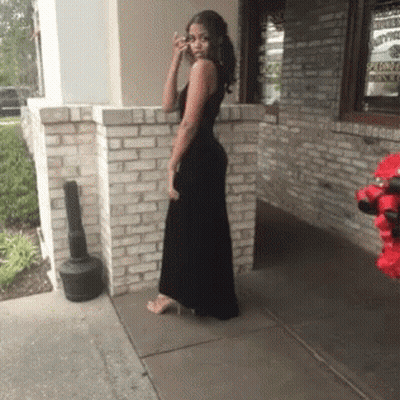 Woman In Black Dress Standing In Front Of Brick Building GIF