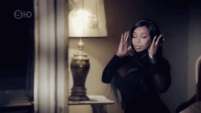 Woman In Black Dress Standing In Front Of Lamp GIF