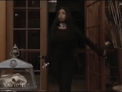 Woman In Black Dress Standing In Front Of Wooden Door GIF