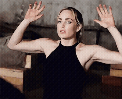 Woman In Black Dress Standing With Hands Up GIF