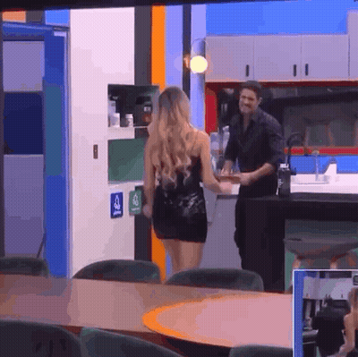 Woman in Black Dress Walking Toward Man in Black Shirt in Kitchen