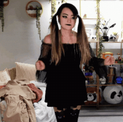 Woman In Black Dress With Pigtails Dancing In Living Room GIF