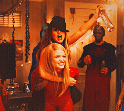 Woman In Black Hat Carrying Woman In Red Outfit GIF