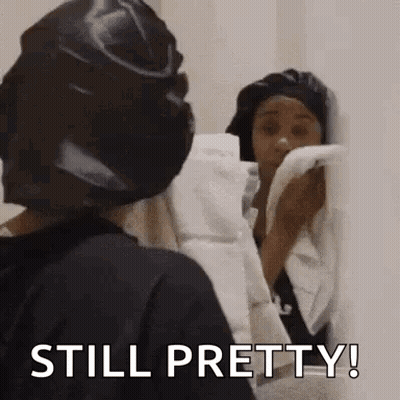 Woman In Black Hat Holding Towel Looking Mirror GIF