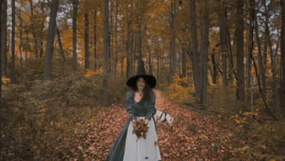 Woman In Black Hat Throwing Leaves In Forest GIF